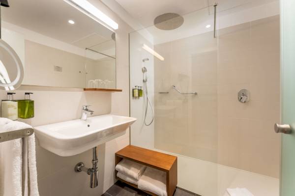 Badezimmer im ARTIEM Audax Hotel mit Dusche, Waschbecken und Handtüchern.