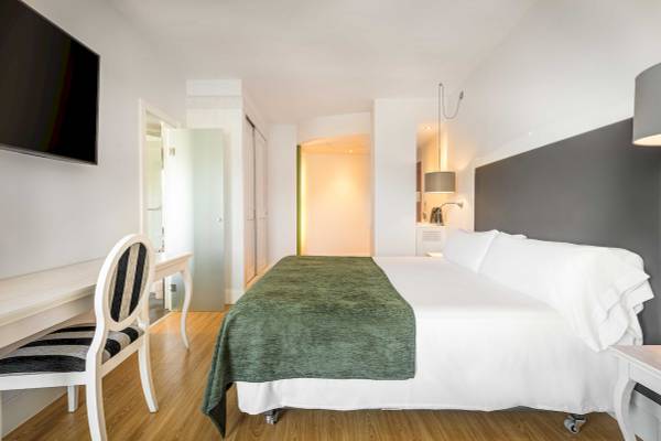 Hotelzimmer im ARTIEM Audax mit einem Bett, grüner Decke, Fernseher und Schreibtisch