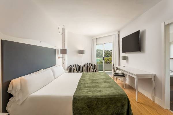 Innenansicht eines Zimmers im ARTIEM Audax Hotel mit einem Bett, Schreibtisch und einem Balkon.