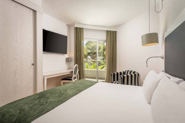 Innenansicht eines Zimmers im ARTIEM Audax Hotel mit Bett, Schreibtisch und Fernseher.