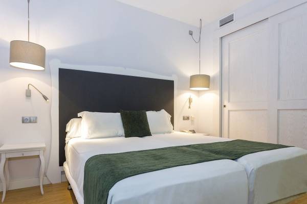 Doppelbett-Zimmer im ARTIEM Audax Hotel mit weißem Bettzeug und grünen Kissen.