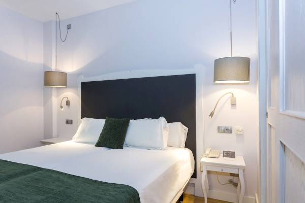 Bett im Hotelzimmer des ARTIEM Audax mit weißen Laken, Kissen und grüner Decke