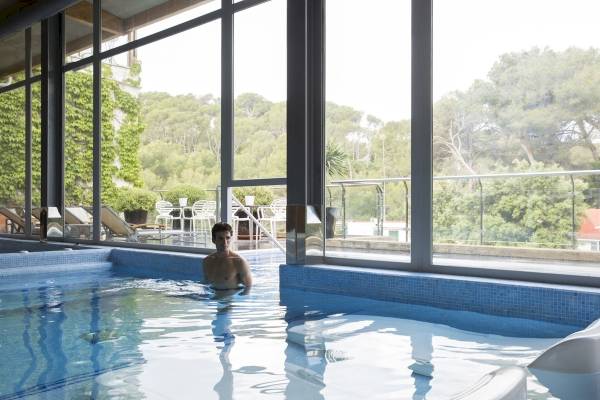 Mann im Innenpool des ARTIEM Audax Hotels mit Blick nach draußen