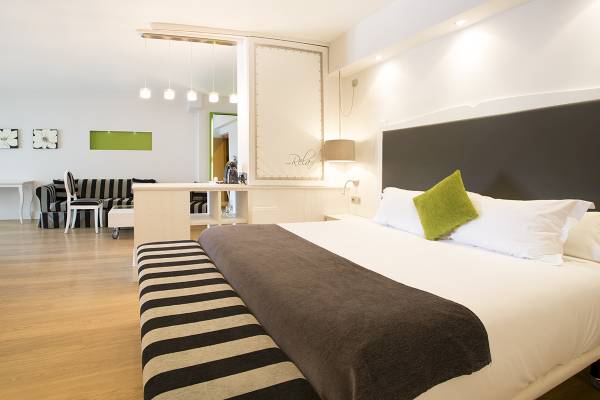 Schlafzimmer im ARTIEM Audax Hotel mit einem Bett, grünem Kissen und weißen Decken.