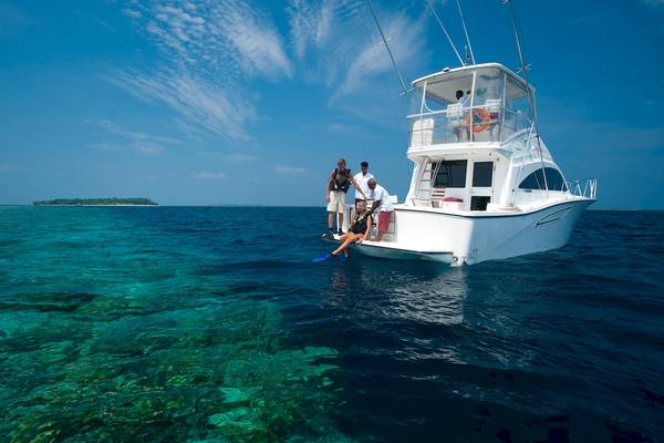Ein Segelboot mit Touristen im Meer, eine Person sitzt auf dem Rand