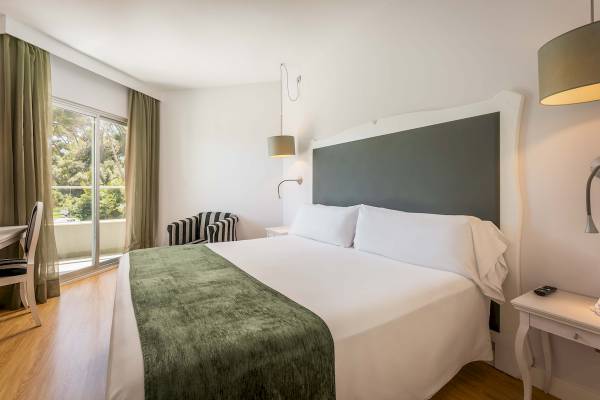 Ein elegantes Hotelzimmer im ARTIEM Audax mit einem großen Bett und grünen Vorhängen.