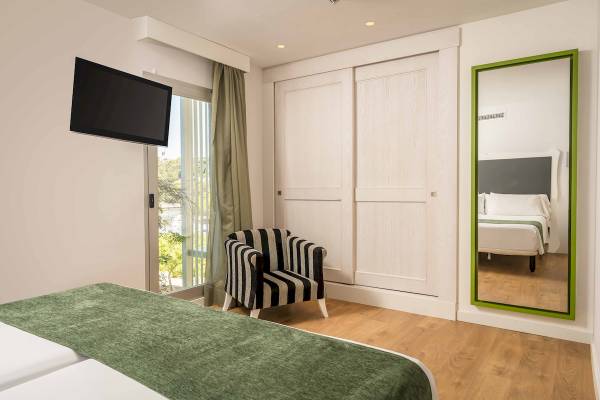 ARTIEM Audax Hotelzimmer mit Fernseher, Spiegel, Bett und Stuhl.