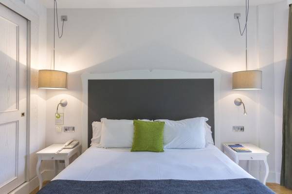 Hotelzimmer im ARTIEM Audax mit weißem Bett und grünem Kissen.