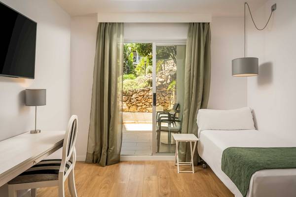Innenansicht eines Zimmers im ARTIEM Audax Hotel mit Schreibtisch, Stuhl, Lampe und Terrassentür