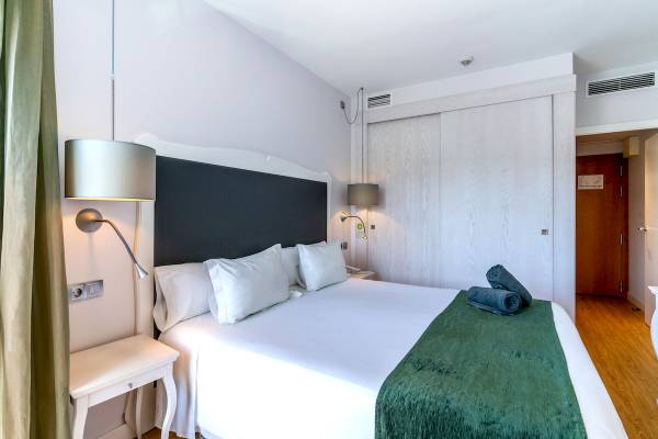 Hotelzimmer im ARTIEM Audax mit einem Bett, Kissen, Decken und Lampen.