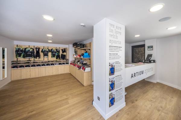 Innenansicht des ARTIEM Audax Sport Shops mit Ausstellungswänden und Sportbekleidung.
