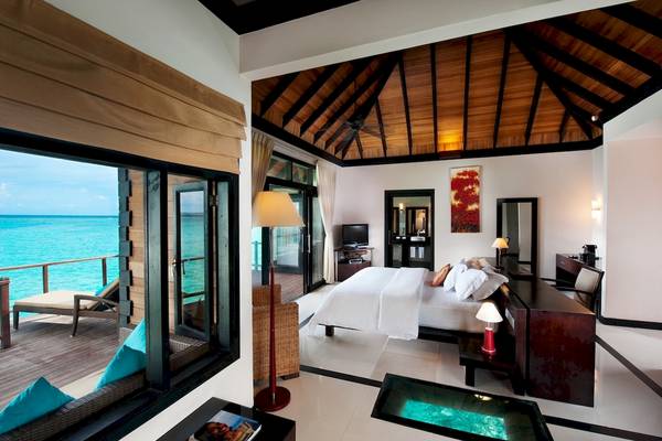 Ein elegantes Hotelzimmer mit einem großen Bett, Blick auf das Meer und einer offenen Terrasse.