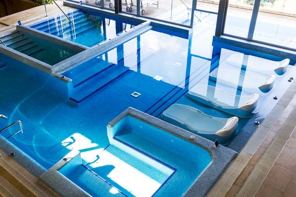 Ein modernes Schwimmbad im ARTIEM Audax Hotel mit separaten Bereichen und Liegestühlen.