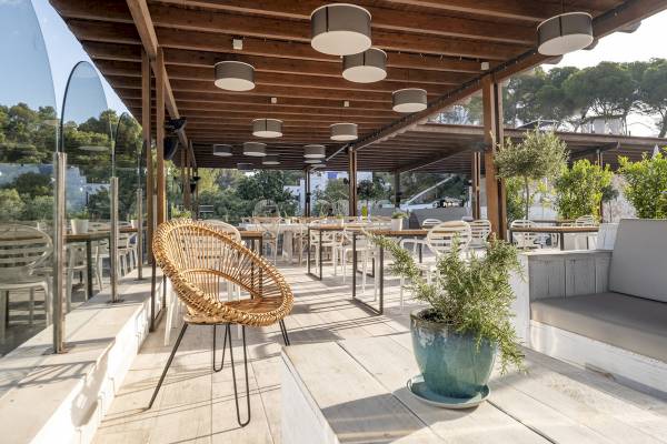 Terrasse des ARTIEM Audax Hotels mit Tischen, Stühlen und Pflanzen.