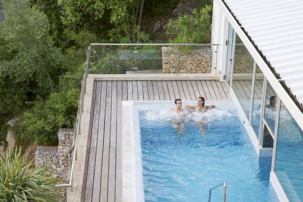 Außenbereich des ARTIEM Audax Hotels mit einem Schwimmbad, zwei Personen schwimmen.