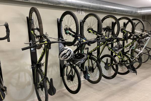 Fahrräder sind in einer Reihe in einer Garage aufgehängt, darunter ein Fahrrad mit Helm, das an einem schwarzen Ständer befestigt ist.