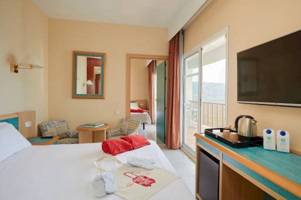 Innenansicht eines Hotelzimmers im Sol Milanos Pinguinos, mit Bett, Tisch, Fernseher und Balkon.
