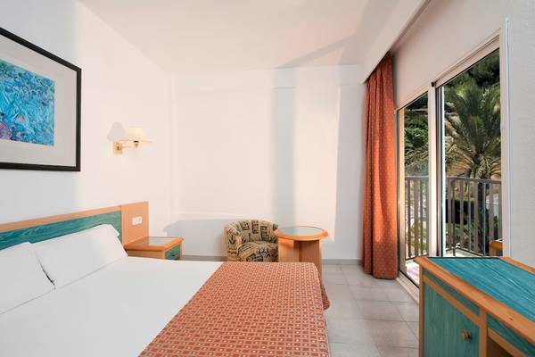 Hotelzimmer des Sol Milanos Pinguinos mit Bett, Tisch, Sessel, Balkon und Gemälde.