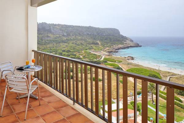 Ein Balkon mit Meerblick im Sol Milanos Pinguinos Hotel mit einem Tisch, zwei Stühlen und Getränken.
