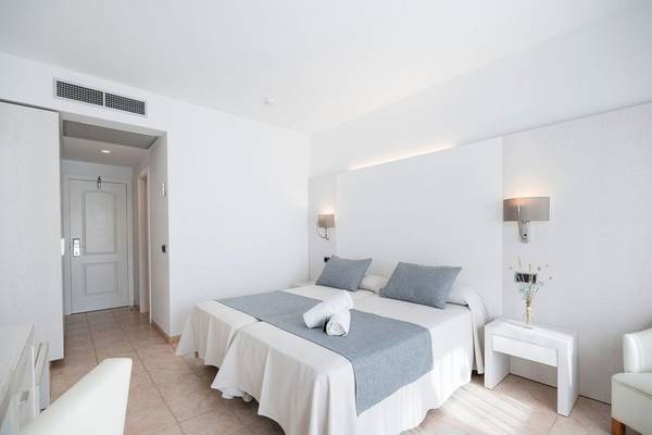 Hotelzimmer im Princesa Playa mit zwei Betten, weißen Wänden und einem weißen Nachttisch.