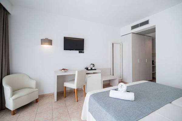 Hotelzimmer im Princesa Playa mit Bett, Schreibtisch, Fernseher und weißem Interieur.