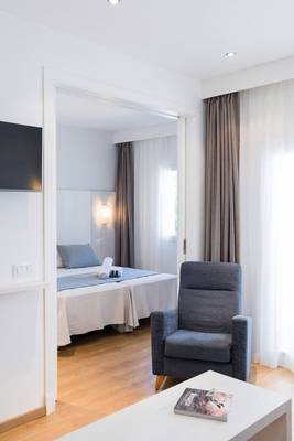 Schlafzimmer im Princesa Playa Hotel mit Doppelbett, Stuhl und Fernseher.