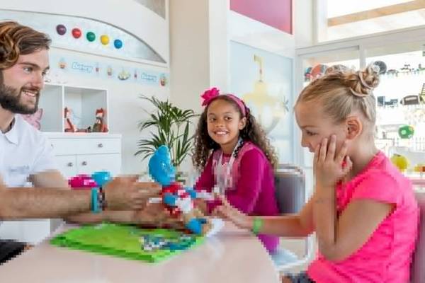 Ein Mitarbeiter des Barcelo Fuerteventura Castillo Hotels spielt mit zwei Kindern an einem Tisch.