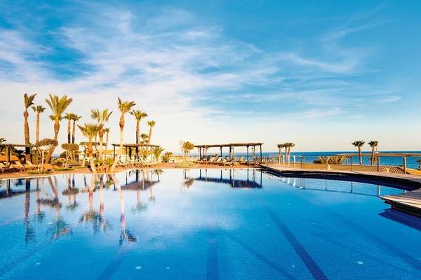 Ein großer Swimmingpool mit Palmen und Sonnenliegen am Punta Prima Resort & Spa.