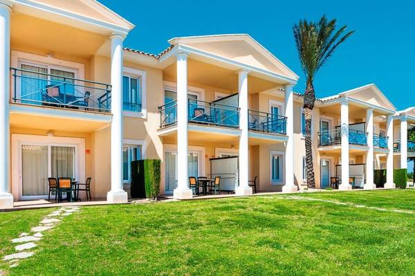 Außenansicht des Punta Prima Resort & Spa mit mehreren Reihen von Gebäuden und grünem Rasen.