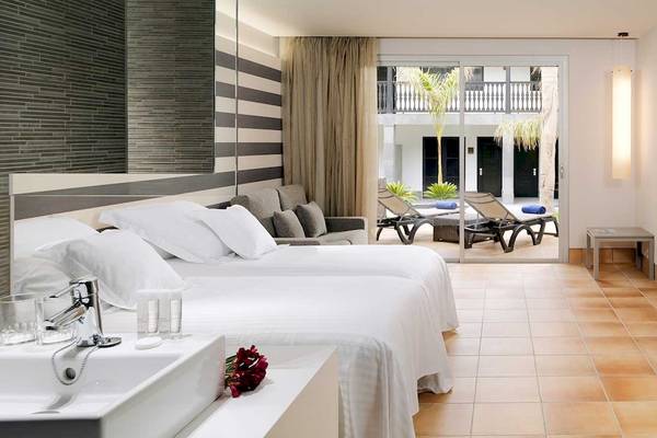 Hotelzimmer im Barcelo Fuerteventura Castillo mit zwei Betten, Wohnzimmerbereich und Terrasse.