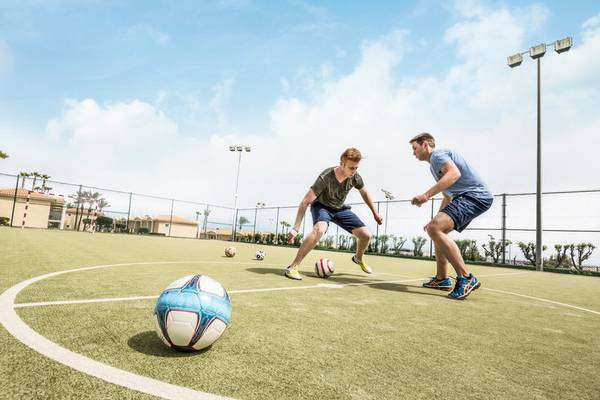 Zwei Männer spielen Fußball auf einem Feld im Punta Prima Resort & Spa.