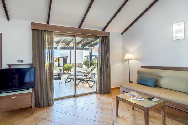 Innenansicht eines Hotelzimmers mit Bett, Fernseher und Balkon.