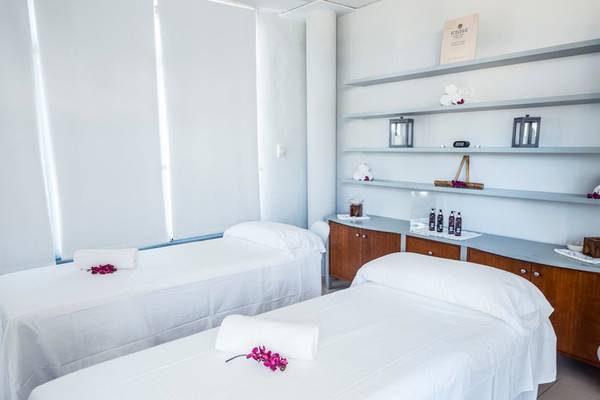 Massageraum im Punta Prima Resort & Spa mit zwei Betten und weißen Laken, auf denen Blumen liegen.