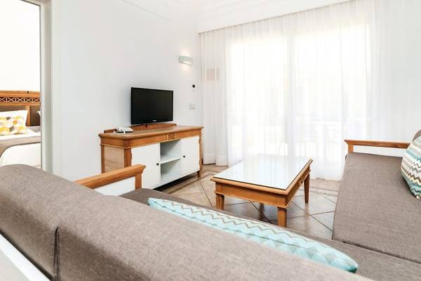 Innenansicht des Wohnzimmers im Punta Prima Resort & Spa mit Fernseher, Couch, Tisch und Bett