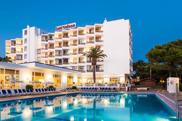 Außenansicht des Lord Nelson Hotels mit Pool bei Nachtbeleuchtung.