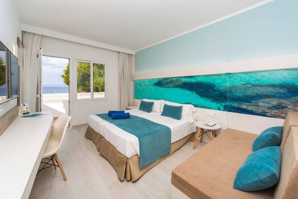 Innenansicht eines Zimmers im Globales Lord Nelson Hotel mit einem großen Bett und einem Ausblick auf das Meer.