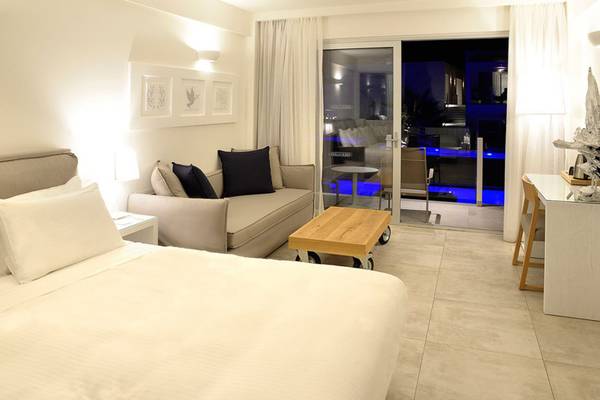 Innenansicht des Schlafzimmers im Insula Alba Resort & Spa mit Bett, Sofa und Glastür.