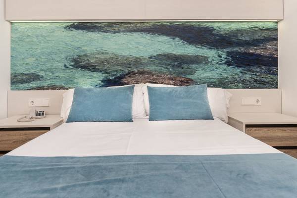Schlafzimmer im Globales Lord Nelson Hotel mit blauem Ozeanbild und bequemem Bett.