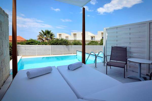 Außenbereich des Insula Alba Resorts mit zwei Lounge-Liegen, Tisch, Stühlen und Swimmingpool.
