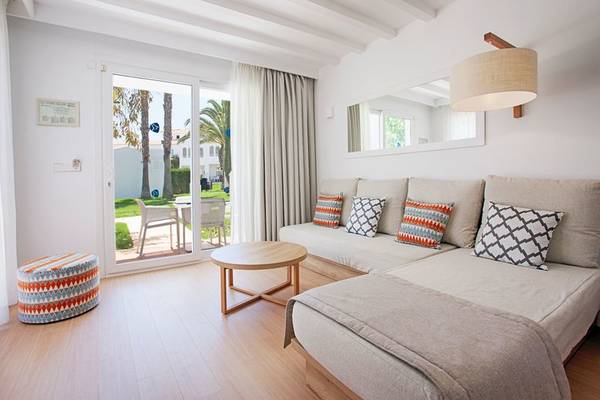 Wohnzimmer im Grupotel Aldea Cala'n Bosch mit Schlafsofa, Tisch und offener Terrasse.