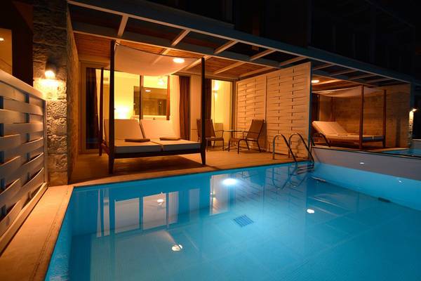 Poolbereich des Insula Alba Resort & Spa mit beleuchteten Sonnenliegen und umliegenden Möbeln.