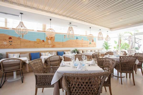 Innenansicht des Restaurants im Grupotel Aldea Cala'n Bosch mit dekorierten Tischen und Stühlen.