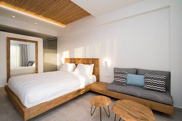 Innenansicht eines Schlafzimmers im Insula Alba Resort & Spa mit Bett, Couch, Spiegel und Holztischen.