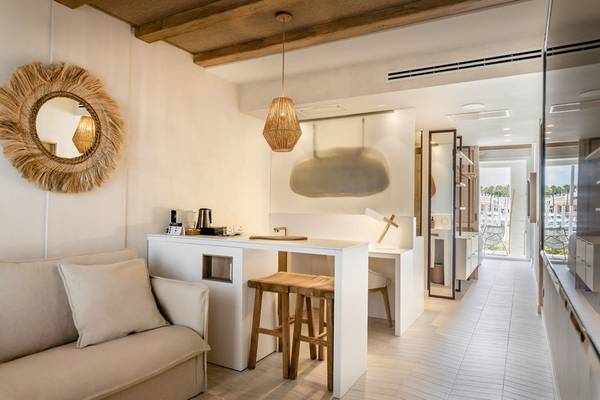 Innenansicht einer Suite im Lago Resort Menorca mit offener Küche, Essbereich und Sofa.