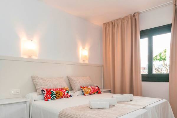 Schlafzimmer im Beach Club Menorca mit einem Bett, Kissen, und Lampen.