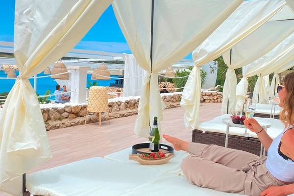 Frau auf einem Liegestuhl auf der Terrasse des Beach Club Menorca mit Blick auf das Meer