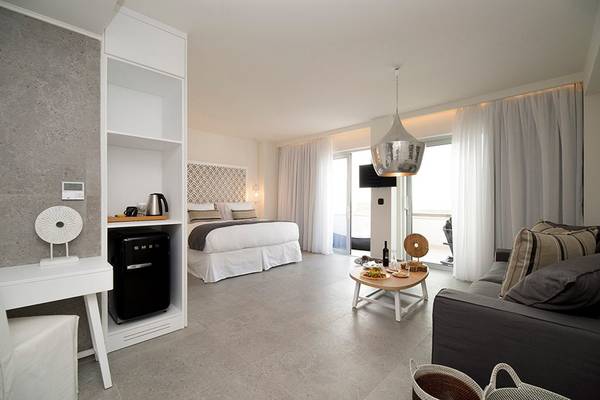 Modernes Zimmer im Insula Alba Resort & Spa mit Bett, Sofa, Tisch und Minibar.