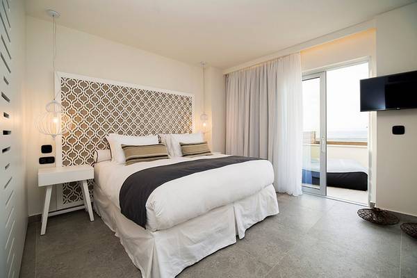 Innenansicht eines Schlafzimmers im Insula Alba Resort & Spa mit einem großen Bett, einem Nachttisch und einer Terrasse.