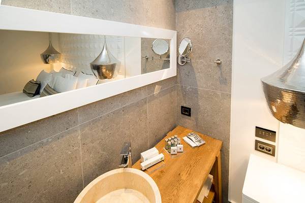 Badezimmer im Insula Alba Resort & Spa mit grauen Fliesen, weißem Waschbecken und Spiegeln.