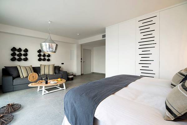 Innenansicht eines Schlafzimmers im Insula Alba Resort & Spa mit Bett, Couch und Tisch.
